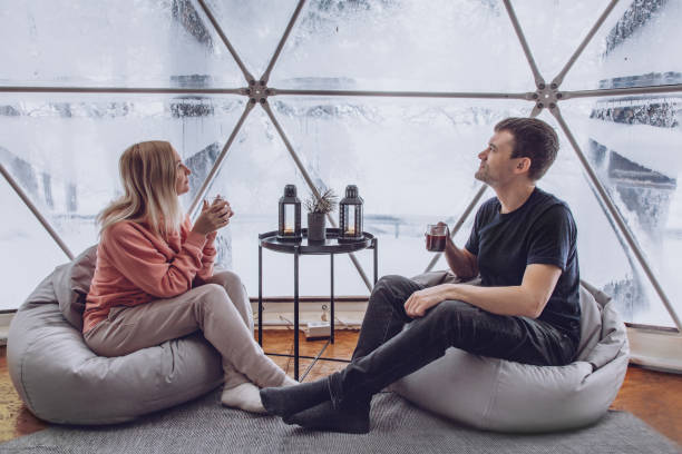 Pár teázik a geodóm belsejében, háttérben téli erdő